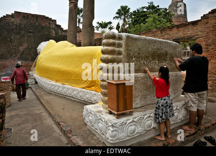 Thaïlande - les visiteurs à peu de mérite en appuyant sur des parcelles de feuille d'or sur le Bouddha couché du Wat Chai Mongkol à Ayutthaya Banque D'Images