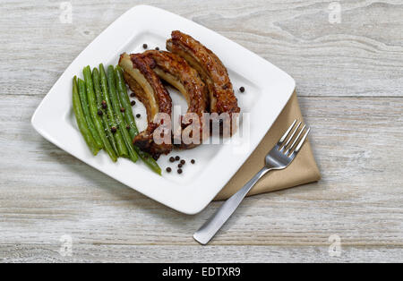 Close up de porc grillées fraîchement cuit de porc, haricots verts sur plaque blanche avec fourchette et serviette en tissu Banque D'Images