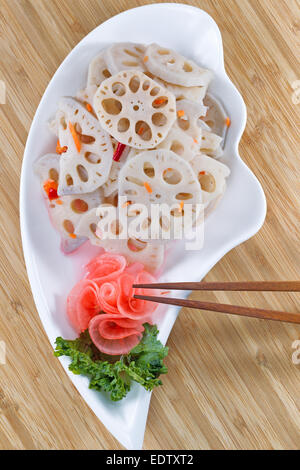 Vue de dessus de l'image verticale de l'eau, le radis chinois lotus blanc dans un plat, avec des baguettes de bambou naturel contexte Banque D'Images