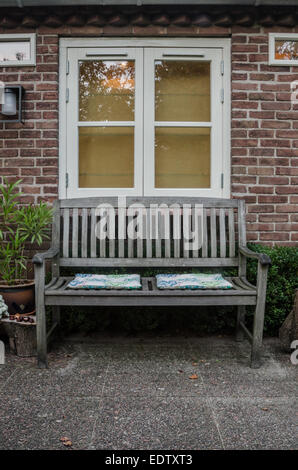 Un jardin d''un coin salon avec un banc en bois et coussins Banque D'Images