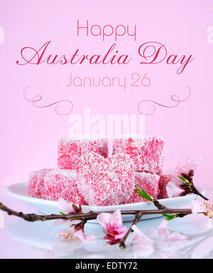 Style australien fait maison en forme de coeur rose petits gâteaux lamington avec fleur de printemps sur une table de réflexion Banque D'Images