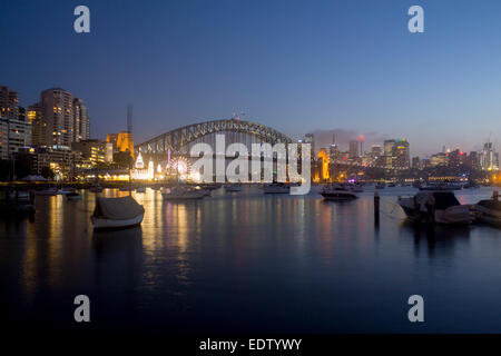 Lavender Bay bateaux en vue sur le port de Sydney Harbour Bridge CBD skyline skyscrapers et Luna Park la nuit Sydney NSW Australie Banque D'Images