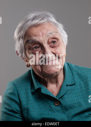 Femme âgée avec expression positive dans un studio shot et isolé sur fond gris Banque D'Images