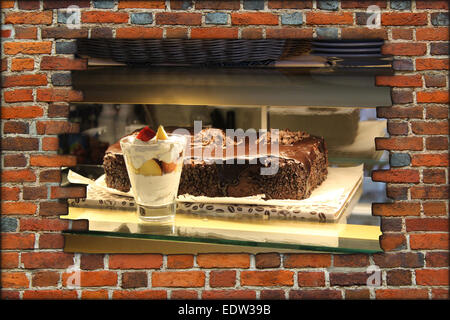 Trou dans le mur de brique et vue de comptoir avec des glaces et des gâteaux Banque D'Images