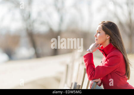 Jolie jeune femme en robe rouge par la clôture en bois Banque D'Images