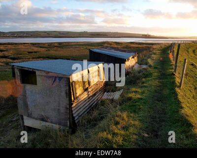 Deux cabanes rustiques fabriqués à partir de tôle ondulée sur le bord de la rivière Taw tidal river, Ilfracombe, Devon, UK Banque D'Images