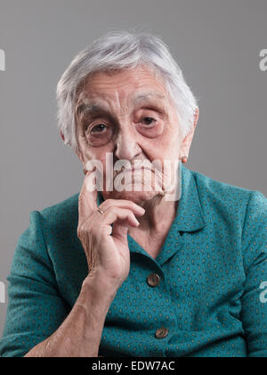 Femme âgée portrait dans un studio photo. Vieille Femme avait sa main sur le menton et triste Banque D'Images