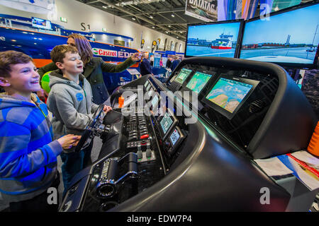 Londres, Royaume-Uni. 9 janvier, 2015. Deux garçons ont un rendez-vous sur un simulateur de navigation Raymarine sophistiqué qui a été connecté à un vrai moteur console à partir d'un Sunseeker Predator. Le MCG FX London Boat Show, qui aura lieu du 09-18 janvier 2015 à l'ExCel Centre, Docklands, Londres. 09 Jan 2015. Crédit : Guy Bell/Alamy Live News Banque D'Images