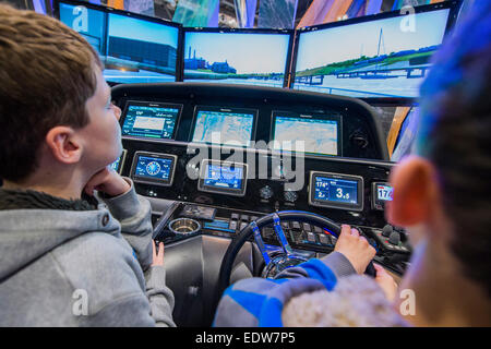 Londres, Royaume-Uni. 9 janvier, 2015. Deux garçons ont un rendez-vous sur un simulateur de navigation Raymarine sophistiqué qui a été connecté à un vrai moteur console à partir d'un Sunseeker Predator. Le MCG FX London Boat Show, qui aura lieu du 09-18 janvier 2015 à l'ExCel Centre, Docklands, Londres. 09 Jan 2015. Crédit : Guy Bell/Alamy Live News Banque D'Images