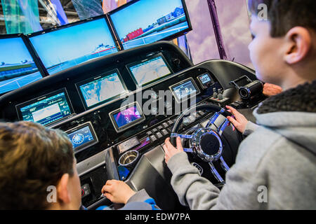 Londres, Royaume-Uni. 9 janvier, 2015. Deux garçons ont un rendez-vous sur un simulateur de navigation Raymarine sophistiqué qui a été connecté à un vrai moteur console à partir d'un Sunseeker Predator. Le MCG FX London Boat Show, qui aura lieu du 09-18 janvier 2015 à l'ExCel Centre, Docklands, Londres. 09 Jan 2015. Crédit : Guy Bell/Alamy Live News Banque D'Images