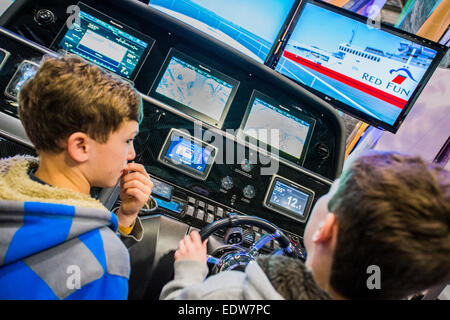 Londres, Royaume-Uni. 9 janvier, 2015. Deux garçons ont un rendez-vous sur un simulateur de navigation Raymarine sophistiqué qui a été connecté à un vrai moteur console à partir d'un Sunseeker Predator. Le MCG FX London Boat Show, qui aura lieu du 09-18 janvier 2015 à l'ExCel Centre, Docklands, Londres. 09 Jan 2015. Crédit : Guy Bell/Alamy Live News Banque D'Images