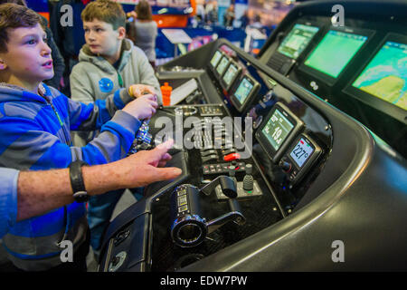 Londres, Royaume-Uni. 9 janvier, 2015. Deux garçons ont un rendez-vous sur un simulateur de navigation Raymarine sophistiqué qui a été connecté à un vrai moteur console à partir d'un Sunseeker Predator. Le MCG FX London Boat Show, qui aura lieu du 09-18 janvier 2015 à l'ExCel Centre, Docklands, Londres. 09 Jan 2015. Crédit : Guy Bell/Alamy Live News Banque D'Images