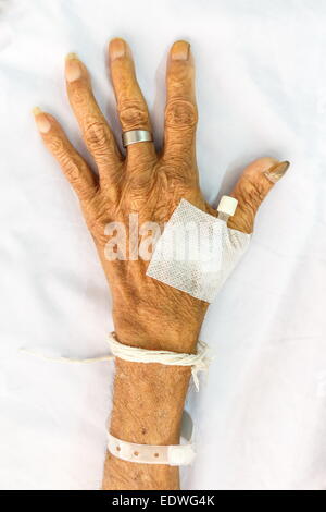 Main de l'ancien patient avec bouchon sur le lit à l'hôpital Banque D'Images