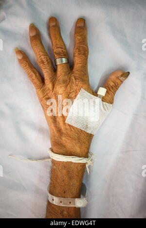 Main de l'ancien patient avec bouchon sur le lit dans un hôpital (style vignette) Banque D'Images