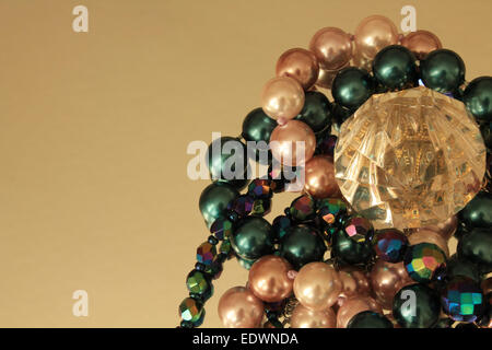 Bijoux Perles et Colliers colorés entourant un cristal sur un miroir entouré d'espace négatif Banque D'Images