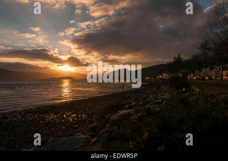 Le coucher de soleil sur le Loch Carron hivers sur une soirée et se reflète sur les bâtiments dans le village. Banque D'Images