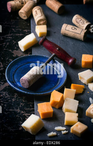 Tire-bouchon vintage, de Cork et de morceaux de fromage sur la table en bois noir Banque D'Images