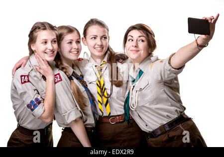 Quatre filles scout photo selfies with mobile phone isolé sur fond blanc Banque D'Images