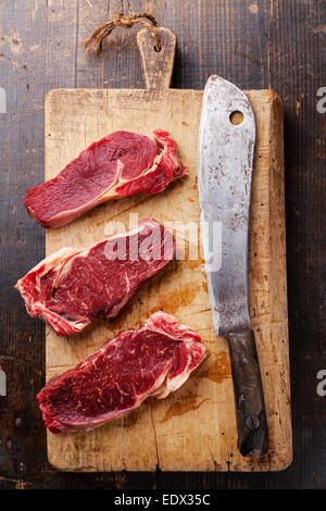 Ribeye steak cru viande fraîche entrecote et couperet à viande sur une planche à découper sur fond de bois Banque D'Images