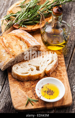 Ciabatta pain tranché et l'huile d'olive extra vierge sur fond de cuisine en bois d'olivier Banque D'Images