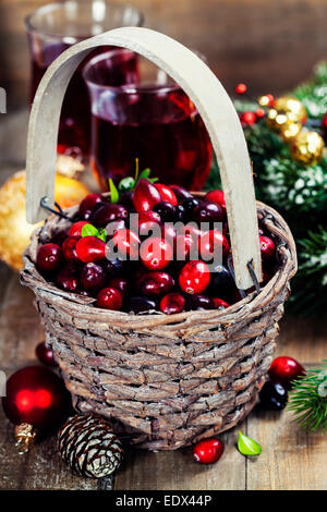 Canneberges rouges frais dans un panier avec des jus de fruits, épices et des branches de pins Banque D'Images