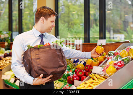 Smiling businessman acheter des légumes frais dans un magasin d'alimentation biologique Banque D'Images