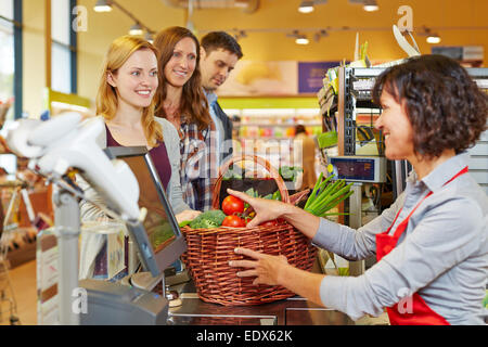 Jeune femme de payer panier de provisions at supermarket checkout Banque D'Images