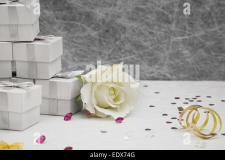 Boîtes de dragées de mariage sur une nappe blanche avec des rubans d'or,bows,Silver Heart confetti et petites décorations de table diamant Banque D'Images