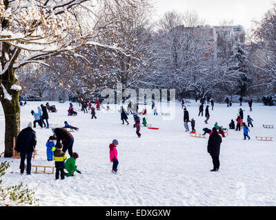 Et les enfants s'amusant avec des toboggans et des traîneaux après de fortes chutes de neige en hiver Parc Public, Mitte, Berlin Banque D'Images