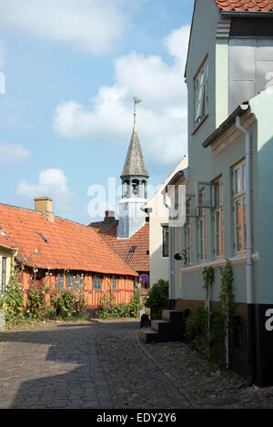 Une rue pavée en pierre bordée de cottages traditionnels danois sur Overgade à Ebeltoft, Danemark la tour de l'horloge est Ebeltof Banque D'Images