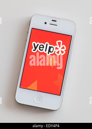 L'écran d'accueil et de l'emblème de l'Yelp mobile app sur un Apple iPhone 4 blanc. Banque D'Images