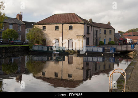 Bâtiment historique rénové bâtiment de l'entrepôt et 2 bateaux amarrés, reflétée dans l'eau calme du bassin du canal - Canal de Ripon, North Yorkshire, Angleterre, Royaume-Uni. Banque D'Images