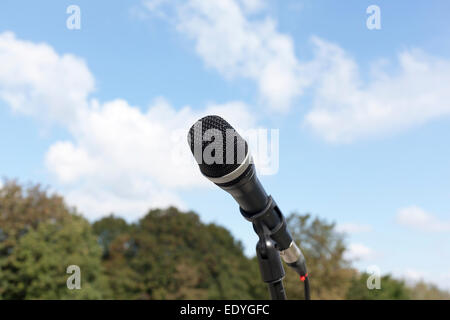 Microphone dans l'accent contre les arbres et ciel brouillé Banque D'Images