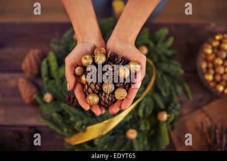 Close-up of female hands avec cônes de sapin et boules d'or Banque D'Images