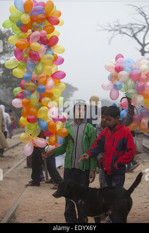 Dhaka, Bangladesh. Jan 11, 2015. Garçon transporte bangladais des ballons pour vendre pendant qu'il observe les dévots musulmans à pied pour assister à la prière finale de la Congrégation islamique de trois jours sur les rives de la rivière Turag à Tongi, 20 kilomètres (13 milles) au nord de la capitale Dacca. Des centaines de milliers de Musulmans ont participé au congrès annuel de l'événement de trois jours qui est l'un des plus grands rassemblements religieux détenu depuis 1960 pour relancer les principes islamiques. Il dévalorise la politique et appelle à la paix. © Zakir Hossain Chowdhury/ZUMA/Alamy Fil Live News Banque D'Images