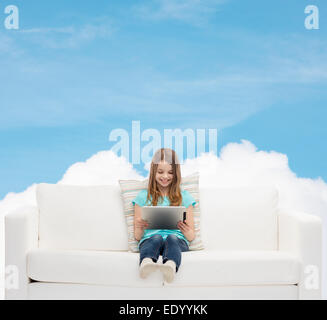 Little girl sitting on sofa with tablet pc Banque D'Images