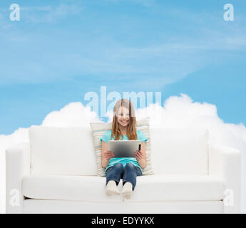 Little girl sitting on sofa with tablet pc Banque D'Images