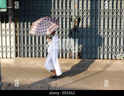 L'homme bouddhiste avec parapluie contre sun walking in street, Bangkok, Thaïlande, Asie du sud-est. Banque D'Images