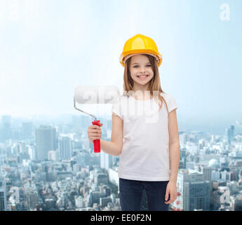 Smiling little girl in helmet with paint roller Banque D'Images