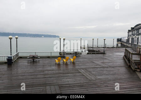 Chaises jaune sur le quai donnant sur l'océan sur un matin brumeux à Seattle. Banque D'Images