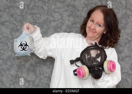 Woman is holding un masque à gaz dans une main, et la corbeille avec le symbole biohazard dans l'autre, avec un fond neutre Banque D'Images