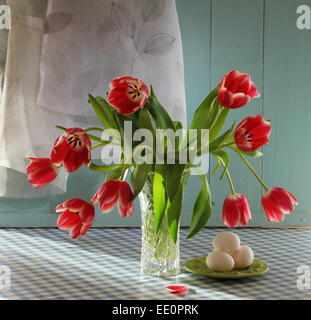 Tulipes rouges dans un vase de cristal avec des oeufs, comme still life Banque D'Images