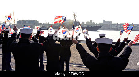 République de Corée marins agitent des drapeaux comme ils se félicitent de la classe Arleigh Burke destroyer lance-missiles USS Mustin lors d'une visite du port le 11 janvier 2015, Donghae en Corée du Sud. Mustin est stationné à Yokosuka, Japon, dans le cadre de la 7ème Flotte américaine déployées à l'avant. Banque D'Images