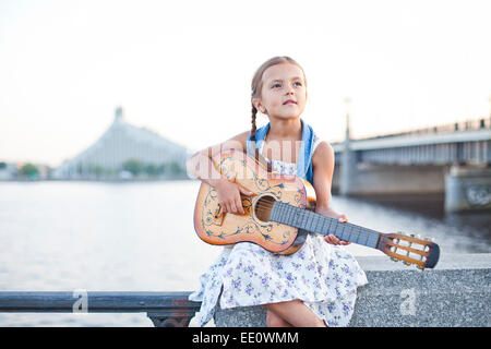 Girl playing guitar sur river embankment Banque D'Images