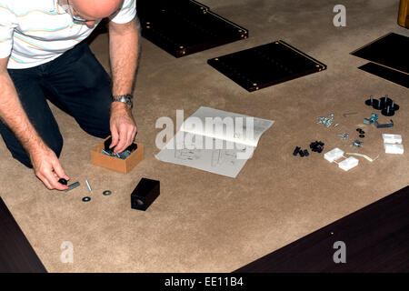 Cet homme est l'assemblage de meubles emballés à plat. Banque D'Images