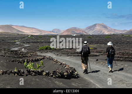 Deux personnes marchant sur un chemin de terre sentier à travers les vignes à La Geria, Lanzarote, îles Canaries, Espagne Banque D'Images