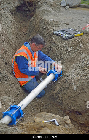 Plombier resserre les menuisiers sur les tuyaux d'une fracture du système de drainage des eaux pluviales Banque D'Images