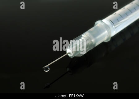 Seringue avec une liste déroulante sur fond noir. Focus sélectif. Banque D'Images