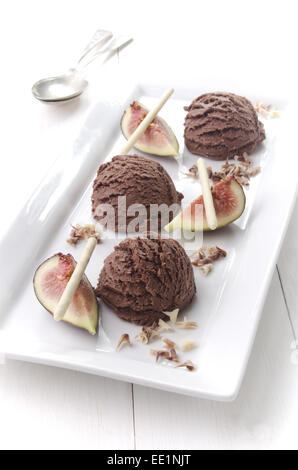 Glace au chocolat avec des bâtons de chocolat blanc, figues et copeaux de chocolat sur une plaque blanche Banque D'Images