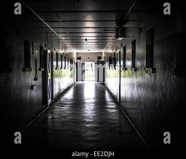 Un couloir sombre dans la prison principale complexe sur Robben Island, Cape Town, Afrique du Sud. Les portes extérieures sont ouvertes montrant la liberté. Banque D'Images